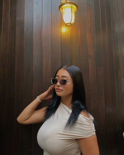 Woman wearing sunglasses against a wooden wall with a lamp.